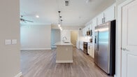 This well-designed single-floor residence offers a thoughtful layout that balances open communal living with comfortable private spaces. The heart of the home is a contemporary open-concept kitchen that flows seamlessly into the living area. Crisp white shaker-style cabinetry lines the kitchen walls, complemented by a classic subway tile backsplash, granite countertops, and a full suite of stainless steel appliances including a refrigerator with ice maker, built-in microwave, and range. A generously sized center island with a granite surface and integrated sink serves as both a functional workspace and a natural gathering point, illuminated from above by a trio of stylish pendant lights. Crown molding adds an elegant finishing touch to the kitchen and living areas, while warm-toned hardwood-style flooring runs throughout the main spaces.

The bedrooms are carpeted for comfort and filled with natural light through multiple windows fitted with blinds. Ceiling fans in each bedroom provide year-round climate control. The bathroom is finished with granite countertops, white cabinetry with matte black hardware, and hardwood-style flooring. It features a tiled soaking tub and shower combination, along with convenient access to a spacious walk-in closet. Throughout the home, a neutral color palette and clean architectural lines create a bright, modern, and welcoming atmosphere.