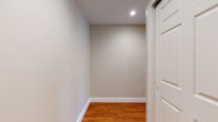 This single-floor unit offers a clean, functional layout with a cohesive design throughout. Warm-toned hardwood flooring runs through the living areas, bedrooms, and hallways, lending a sense of continuity and warmth across the space. Neutral, light-gray walls complement the floors and contribute to a bright, airy ambiance.

The kitchen is well-equipped and efficiently designed, featuring honey-toned wood cabinetry, granite countertops with subtle earth-tone patterning, a suite of black appliances including a gas range and refrigerator, and light ceramic tile flooring. Recessed lighting above provides practical illumination.

The living areas are generously proportioned, with large windows that invite natural light and offer views of the surrounding neighborhood and greenery. Wall-unit air conditioners and baseboard heating ensure year-round climate control. Recessed lighting adds a polished touch in select areas.

The bedrooms are spacious and well-lit, each featuring hardwood flooring and windows that frame outdoor views. A dedicated hallway with a recessed ceiling light and a paneled white door leads to additional rooms, providing a practical transition between areas.

The bathroom is finished with neutral ceramic tile, featuring a glass-enclosed corner shower with decorative mosaic tile accents, a clean toilet, and tile flooring — offering a tidy and functional space. Overall, the unit presents a move-in-ready environment with consistent finishes throughout.