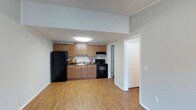 This deluxe one-bedroom, one-bathroom unit offers a practical and comfortable single-floor layout designed to maximize functionality. The open-concept design seamlessly connects the kitchen and living areas, creating a spacious, airy feel throughout.

The kitchen is well-appointed with warm-toned wooden cabinetry offering ample storage, black appliances including a full-size refrigerator, an electric range, and a built-in microwave/ventilation unit above the stove. A double-basin sink with a window view adds convenience to the workspace. The kitchen is brightened by a flush-mount ceiling light fixture, ensuring a well-lit cooking environment.

Durable hardwood-style flooring extends throughout the unit, providing a cohesive and easy-to-maintain surface. The neutral gray walls and white trim offer a clean, modern backdrop adaptable to a variety of décor styles. A closet with bifold doors is conveniently positioned near the kitchen, providing additional storage. The overall layout is efficient and thoughtfully designed, making it an ideal space for comfortable everyday living.