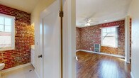 Located at 637 N Bronson Ave in the heart of Los Angeles, CA, this single-floor unit blends classic architectural character with functional living spaces. The most striking design element throughout is the exposed red brick walls, which lend warmth and industrial charm to the interior. Rich, hardwood floors run throughout the main living areas, complementing the brick and adding a timeless, inviting quality to the space.

The main living area is generously proportioned, featuring dual windows that allow natural light to pour in from multiple angles, illuminating the polished hardwood floors. A ceiling fan with integrated lighting provides both comfort and additional illumination. A wall-mounted HVAC unit ensures year-round climate control.

The galley-style kitchen is efficiently laid out, featuring white cabinetry, dark countertops, a stainless steel sink, and white appliances including a full-size refrigerator and range. The warm hardwood flooring continues here, and a doorway leads further into the unit.

The bathroom offers a classic aesthetic with white hexagonal mosaic tile flooring, a soaking tub, and a window with natural light. The exposed brick wall continues into this space, tying the design together cohesively.

An additional room with smooth walls and hardwood floors provides flexible living or sleeping space, also benefiting from natural light and a ceiling fan.