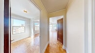 Located in Seattle's vibrant University District at 4337 15th Ave NE, this 1-bedroom, 1-bathroom unit showcases timeless character throughout. The spacious bedroom is the highlight of the home, featuring classic parquet hardwood flooring, a ceiling fan, and multiple windows that flood the room with natural light and offer pleasant views of the surrounding Seattle cityscape. Elegant French doors with glass pane detailing connect the bedroom to adjacent spaces, adding a refined architectural touch. Crown molding and crisp white baseboards throughout reinforce the unit's classic aesthetic. The bathroom retains its vintage charm with classic white penny tile flooring, a pedestal sink, and traditional fixtures. The kitchen offers granite-style countertops and a coil-top range, providing functional cooking space. A dedicated laundry area and two closets deliver practical storage solutions. The hallway connects all areas efficiently, making smart use of the compact floor plan. Warm, neutral tones on the walls complement the natural wood tones of the parquet floors and rich mahogany-stained doors, creating a cohesive and inviting atmosphere throughout this well-appointed Seattle residence.