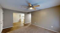 This single-floor, three-bedroom, two-bathroom home in Phenix City, Alabama offers a practical and well-organized layout. The living room serves as the central gathering space, featuring a ceiling fan with light fixture and wood-look flooring that flows seamlessly into the dining area and galley-style kitchen. The kitchen is efficiently designed with white shaker cabinetry, light granite-style countertops, a double-basin stainless steel sink, a white electric range, and a full-size refrigerator, providing ample storage and counter space on both sides.

The three bedrooms are carpeted for comfort, each equipped with ceiling fans. The spacious primary bedroom features a set of double French doors that allow natural light to fill the room and provide outdoor access. The secondary bedrooms include windows with blinds and generous closet space, including a double-section closet with wire shelving. The two bathrooms are finished with wood-look vinyl flooring, white vanities, and a tub/shower combination.

Additional functional spaces include a dedicated laundry room, a utility room, and a hallway connecting the living areas to the bedrooms. Textured ceilings and neutral warm-gray wall tones are consistent throughout, lending the home a cohesive and understated aesthetic.