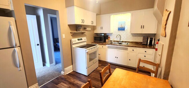 Fully equipped kitchen with oven, microwave, coffee station, and Minnesota-themed art. - 822 E 4th St