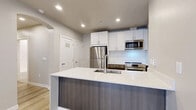 Located at 1960 Argentine St in the historic mountain town of Georgetown, Colorado, this thoughtfully designed 2-bedroom, 2-bathroom single-floor unit offers a clean, modern aesthetic throughout. Light wood-tone flooring flows seamlessly across all living areas, complementing the neutral warm-gray walls and crisp white trim that define the interior palette.

The open-concept kitchen is a standout feature, anchored by a large island with a white quartz countertop, an undermount sink, and a rich dark wood-grain base. White shaker-style cabinetry lines the walls alongside a subway tile backsplash, while stainless steel appliances — including a refrigerator, range, and built-in microwave — complete the modern finish. Recessed lighting illuminates the space efficiently.

Both bedrooms are well-proportioned, with the primary bedroom offering generous closet space via sliding double doors. The bedrooms feature neutral walls and natural light from windows fitted with blinds. Three closets in total provide ample storage throughout the unit.

The two bathrooms reflect a contemporary design sensibility. One features marble-look tile flooring, a floating wood-toned vanity with a backlit mirror, and a walk-in shower. The second bathroom includes a clean tub-shower combination. Additional conveniences include in-unit laundry, a utility room, and a private balcony.