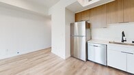 Located at 900 N Ardmore Ave in the heart of Los Angeles, this modern 2-bedroom, 2-bathroom unit offers a thoughtfully designed single-floor layout with contemporary finishes throughout. Light wood-style flooring runs continuously across the living areas, creating a cohesive and airy feel. The open-concept living, dining, and kitchen area forms the heart of the home, anchored by large sliding glass doors that open to a balcony with sweeping views of the Los Angeles skyline and iconic palm trees. The kitchen is well-appointed with stainless steel appliances including a refrigerator, dishwasher, and range, paired with white lower cabinetry, warm wood upper cabinets, and a clean white countertop. Both bedrooms are bright and well-proportioned, featuring large windows that frame outdoor views of the surrounding neighborhood. The primary bedroom includes an en-suite bathroom, while the second bathroom is accessible from the hallway. Each bathroom features a tub-shower combo, modern fixtures, and light wood-tone flooring. Additional conveniences include two closets, a dedicated laundry area, and a connecting hallway. The unit's clean white walls and abundant natural light give the entire space a fresh, contemporary ambiance ideal for urban living.