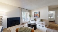 This single-story, 1-bedroom, 1-bathroom unit offers an efficient and thoughtfully designed layout across a compact yet functional floor plan. The combined kitchen and living room serves as the heart of the home, where a standout wood-surround fireplace with a dark tile surround anchors the living area. Natural light pours in through sliding glass doors that lead to an outdoor space, complemented by patterned drapes that add a modern touch. The textured ceiling and neutral walls create a clean, bright ambiance throughout.

The kitchen is outfitted with white cabinetry, light quartz-style countertops, a double stainless steel sink with a matte black faucet, and black appliances including a range and dishwasher. Wood-look flooring adds warmth to the kitchen and flows into the bathroom.

The bedroom offers a comfortable, carpeted retreat with a ceiling fan, a closet, and a window that brings in natural light — with enough space for a dedicated work area. The bathroom features a single-sink vanity with a quartz countertop, a tub-shower combination with tile surround, and wood-look flooring. A utility room rounds out this practical, move-in-ready space.