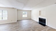 Located at 7035 Rambling Hills Dr in Morrisville, NC, this two-story, four-bedroom, three-bathroom home offers a well-organized layout across two floors. The main level welcomes you through a dedicated entrance that flows into a bright, open living room featuring light wood-look flooring, a textured ceiling, and a classic fireplace with a dark surround — a natural focal point for the space. The kitchen is thoughtfully designed with white cabinetry, granite-look countertops, a peninsula for additional prep or seating space, wood-look flooring, and black appliances including a range, microwave, and refrigerator. A window provides natural light over the sink area. The upper floor hosts the bedrooms, including a generously sized primary bedroom with plush carpet, a walk-in closet, and an en-suite bathroom. Additional bedrooms are carpeted and well-proportioned, sharing access to two full bathrooms, each featuring tub-shower combinations with clean white surrounds and tile flooring. A wooden deck off the back of the home offers serene, private views of a mature tree canopy — a peaceful outdoor retreat. Hallways and a staircase connect the floors efficiently, completing this functional and comfortable home.