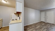 Located at 101 W Wekiwa Rd in Sand Springs, Oklahoma, this single-floor unit offers a practical and straightforward layout designed for comfortable everyday living. The main living area is finished with durable wood-look plank flooring and neutral gray walls, creating a clean, move-in-ready atmosphere. A textured popcorn ceiling runs throughout the common areas, adding a classic residential character. The kitchen is open to the living space via a pass-through counter, and is equipped with a white electric range and upper white cabinetry, providing functional storage and cooking space. The living room features two doors — likely a closet and an entry — alongside a window fitted with horizontal blinds that allow natural light to filter in. The bedroom is carpeted for added comfort and warmth, with a window that brings in additional natural light and a quiet, restful ambiance. The bathroom includes a full-size tub and shower combo with white tile surround, a toilet, wood-tone cabinetry above, and wood-look flooring that ties the space together. A ceiling fan is present in one of the main rooms, adding to the unit's practical amenities. Overall, this space presents a clean, functional, and well-maintained environment suited for a range of occupants.