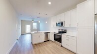 Located at 1023 Gull Ln in Melbourne, FL, this well-designed single-floor residence offers a thoughtfully planned layout across a comfortable footprint. The open-concept living, dining, and kitchen area serves as the heart of the home, anchored by a sleek kitchen featuring white shaker cabinetry, quartz countertops, stainless steel appliances — including a French door refrigerator, electric range, built-in microwave, and dishwasher — and a peninsula with pendant lighting overhead. Light wood-tone flooring flows throughout the main living areas, enhancing the bright, airy atmosphere created by neutral walls and recessed lighting. The living area is equipped with a ceiling fan and connects to a private balcony with outdoor views, accessible through a glass-paneled door. The spacious bedroom is finished with plush carpet, a ceiling fan, and double windows that invite natural light. Two closets provide generous storage, and direct access leads to the full bathroom, which showcases a glass-enclosed walk-in shower with large-format tile, a white vanity with undermount sink, and wood-look flooring. A dedicated laundry area completes this clean, modern residence.