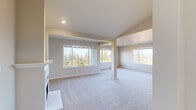 This single-story home is designed with an open and functional layout, highlighted by neutral tones and an abundance of natural light. The main living area is expansive and open-concept, featuring plush light gray carpeting, recessed lighting, and a fireplace. Large windows frame views of mature evergreen trees and surrounding landscape, creating a connection to the outdoors. A structural column defines the transition between living zones while maintaining visual continuity across the space.

The kitchen is a standout feature, finished with white shaker cabinetry, light quartz countertops, a subway tile backsplash, and stainless steel appliances including a refrigerator, range, and microwave. Wood-look flooring, a skylight, and a recessed ceiling add warmth and character. An arched doorway leads further into the home.

The bedrooms are carpeted and well-proportioned, each receiving natural light through sizable windows with outdoor views. One bedroom includes a walk-in closet outfitted with wire shelving and hanging rods for organized storage.

The bathroom is clean and functional, featuring a white vanity with ample storage, a mirror, a window for natural light, and a tub-shower combination. Additional rooms offer flexible, carpeted spaces suitable for varied uses.
