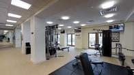 Located at 515 West Ave in Norwalk, Connecticut, this fitness center offers a well-equipped, single-floor workout facility designed to support a comprehensive exercise routine. The space is finished with a clean, functional aesthetic, featuring crisp white walls and a combination of rubber fitness flooring and light-toned hard flooring throughout.

The facility is outfitted with a multi-station cable weight machine, a dedicated free weights area with dumbbells and a weight bench, and additional strength training equipment to accommodate a range of workout preferences. Mounted flat-screen televisions are positioned throughout the space, allowing members to stay entertained during their sessions.

Natural light fills the room through large windows and glass-paneled doors that overlook an outdoor terrace or patio area, creating an open and energizing atmosphere. The space benefits from ample overhead lighting, ensuring visibility in every corner. Ventilation is provided through ceiling-mounted HVAC units, contributing to a comfortable environment year-round.

The layout is thoughtfully organized to allow for ease of movement between stations, making the facility accessible and practical for users of varying fitness levels. Overall, this fitness center provides a bright, well-maintained, and fully equipped environment ideal for residents or members looking to maintain an active lifestyle.