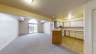 Located at 5811 Sandalwood Dr in Kalamazoo, Michigan, this single-floor residence offers a well-organized layout with a bright, open feel throughout. The living area is a standout feature, boasting vaulted ceilings that rise dramatically alongside a striking arched window and a full-height sliding glass door that opens to an exterior balcony, flooding the space with natural light and outdoor views.

The kitchen flows seamlessly from the living area and is equipped with white cabinetry trimmed in warm oak, generous counter space, a gas range, a dishwasher, and a central island that provides additional workspace and a natural division between the two areas. The tile flooring in the kitchen transitions to plush wall-to-wall carpeting throughout the living and bedroom spaces.

The bedrooms are comfortably sized, each featuring carpeted floors, neutral walls, and windows with blinds that allow for adjustable natural light. The bathroom includes a vanity with oak-accented cabinetry, a tub and shower combination with tile surround, and hardwood-style flooring, offering a clean and functional design. Overall, the space presents a practical and comfortable layout with architectural character, particularly highlighted by the vaulted living area and its generous access to natural light.