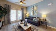 Located at 3340 Shipley St in Ladson, South Carolina, this single-floor residence offers a thoughtfully designed layout with a cohesive, contemporary aesthetic throughout. The kitchen is a functional highlight, featuring dark espresso cabinetry, granite countertops, black appliances including a range, microwave, dishwasher, and refrigerator, along with light wood-style flooring and pendant lighting that adds a warm, modern touch. The open living area is bright and inviting, with large French doors that allow abundant natural light and provide access to an outdoor space. A ceiling fan adds comfort, and the room's layout accommodates both relaxing and entertaining. An adjoining dining area features wall sconce lighting and a cozy atmosphere ideal for meals. Two bedrooms are included — the primary bedroom offers carpeted flooring, a natural light-filled window, and a bold accent wall, while the second bedroom is comfortably sized with soft, neutral finishes. Two bathrooms serve the residence: one with a walk-in glass-door shower and the other featuring a granite-topped vanity with dark wood cabinetry. A dedicated in-unit laundry area with a full-size washer and dryer and overhead shelving completes the practical amenities of this well-rounded home.