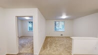 Located at 6940 37th Ave S in Seattle's Brighton neighborhood, this one-bedroom, one-bathroom unit offers a thoughtfully organized single-floor layout. The living area features neutral-toned carpet and white walls, with windows that bring in natural light and offer views of surrounding greenery. The space flows openly between the living room and kitchen, making efficient use of the floor plan.

The kitchen is equipped with light wood cabinetry, a white electric range, refrigerator, microwave, and a single-basin sink, all set on wood-look flooring. The layout follows an L-shaped configuration that maximizes counter and storage space.

The bedroom is a comfortable, carpeted room with a large window overlooking trees, providing a calm, natural atmosphere. A built-in closet with bifold doors and integrated shelving offers practical storage. The room is bright and simply finished with clean white walls.

The bathroom features wood-look flooring, a full bathtub/shower combo, toilet, and vanity with sink. Accessibility is a notable feature, with stainless steel grab bars installed along the walls. A small window provides ventilation and light.

Overall, this unit presents a clean, functional design with consistent finishes throughout, suited for those seeking a practical and well-lit living space in Seattle.