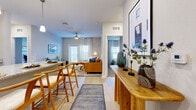 Located at Avida Village Circle in Orlando, FL, this single-story residence offers a thoughtfully designed 2-bedroom, 2-bathroom floor plan with a comfortable and functional layout. Light wood-tone flooring flows through the main living areas, complemented by soft neutral wall tones that create a bright, welcoming ambiance throughout.

The open-concept kitchen is a standout feature, equipped with gray shaker-style cabinetry, granite countertops, stainless steel appliances, recessed lighting, and a large center island with pendant lighting and bar seating — ideal for dining and entertaining. The kitchen connects seamlessly to the dining and living areas, where a ceiling fan and multiple windows allow ample natural light to fill the space.

The living room is generously proportioned, offering an inviting area for relaxation. Both bedrooms feature plush carpeting and dedicated closets, including a spacious walk-in closet with wire shelving systems for organized storage. The primary bedroom provides a comfortable retreat with room for a full furniture arrangement.

Each bathroom includes a granite-topped vanity with white cabinetry, a large mirror, and light wood flooring. A utility room and additional closet space add practicality to the home. The overall design balances modern finishes with a warm, livable aesthetic throughout.