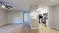 This single-floor residence is designed with a clean, contemporary aesthetic that balances functionality and comfort. The open-concept layout connects the kitchen and living area seamlessly, creating a cohesive and inviting main living space. Light wood-style flooring runs throughout, contributing to a bright and consistent look across all rooms.

The kitchen is well-equipped with white shaker-style cabinetry, black hardware accents, a neutral-toned peninsula with an undermount sink, stainless steel appliances including a range, microwave, and dishwasher, alongside a black refrigerator. White subway tile backsplash adds a classic finishing touch.

The living area is generously proportioned, featuring a ceiling fan with light fixture, a sliding glass door that opens to an outdoor area, and an additional window that draws in natural light. The front entry door anchors one side of the room.

The bedrooms are comfortable and well-lit, each with ceiling fans, windows offering outdoor views, and light neutral walls. Closet space is provided, including a walk-in closet in at least one bedroom, alongside additional standard closets. A dedicated hallway connects the main living spaces to the private rooms.

The bathroom includes a full-size soaking tub with a tiled shower surround, a toilet, and a clean, minimalist design. The overall ambiance of this residence is fresh, modern, and move-in ready.