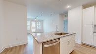 Located at 8402 IBM Drive in Charlotte, NC, this single-floor, two-bedroom, two-bathroom residence offers a well-designed layout across a comfortable footprint. The open-concept kitchen and living area serves as the heart of the unit, where a granite-topped island with an undermount sink and built-in dishwasher anchors the space. White shaker-style cabinetry, a herringbone tile backsplash, and a full suite of stainless steel appliances—including a refrigerator, range, and microwave—complete the kitchen. Light wood-style flooring flows throughout the common areas, complemented by recessed lighting and a ceiling fan in the living room. A glass door with flanking windows fills the living area with natural light and provides exterior views. The primary bedroom is a generously sized retreat featuring plush carpeting, a ceiling fan, and a window overlooking the exterior. The second bedroom also features soft carpeting and a double-door closet. Both bathrooms are finished with granite vanity tops and wood-style tile flooring; one includes a glass-enclosed shower, while the other offers a full tub-shower combination. Clean white walls and consistent finishes throughout create a cohesive, modern aesthetic.