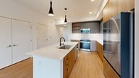 Located at 403 NE 76th St in Redmond, WA, this modern single-floor unit offers 1,090 square feet of contemporary living across 4 bedrooms and 2 bathrooms. The open-concept kitchen and living area serves as the heart of the home, featuring a large center island with a quartz countertop and undermount sink, warm wood-grain cabinetry, matte gray upper cabinets, white subway tile backsplash, stainless steel appliances, and stylish pendant lighting. Light bamboo-style flooring flows consistently throughout the entire unit, enhancing the clean, cohesive aesthetic. The four bedrooms are bright and airy, with large windows that invite abundant natural light and outdoor views of the surrounding Redmond landscape. The 170 sq ft primary bedroom includes ceiling fan and ample space. Two well-appointed bathrooms serve the unit: one features a tub-shower combo with white tile surround and a wood-vanity with an LED-backlit mirror, while the second offers a glass-enclosed walk-in shower with floor-to-ceiling white tile and matte black hardware. Additional spaces include two hallways, a dedicated closet, and ceiling fans in select bedrooms for year-round comfort. The unit presents a clean, modern design throughout.