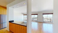 This single-floor residence offers a thoughtfully designed layout with a clean, contemporary aesthetic throughout. The open-concept living and dining area is anchored by warm hardwood flooring and crown molding, with large floor-to-ceiling windows and sliding glass doors that frame sweeping city views and flood the space with natural light. A private balcony extends the living area outdoors, perfect for taking in the urban panorama.

The kitchen is well-equipped and stylish, featuring warm wood cabinetry, dark stone countertops, a striking blue mosaic tile backsplash, and a full suite of stainless steel appliances including a refrigerator, range, and built-in microwave. A central island with a matching dark countertop provides additional prep space and casual seating.

The bedrooms are carpeted for comfort and benefit from generous natural light through large windows with wooden roller shades, offering continued city views. A hallway with hardwood flooring connects the living spaces to the private quarters.

The bathroom is a refined retreat, finished entirely in marble tile — from floor to ceiling — and featuring a deep soaking tub enclosed by a frameless glass shower surround with a handheld showerhead, lending the space a spa-like quality. Recessed and flush-mount lighting throughout the residence completes its polished, functional design.
