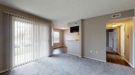 Located at 1551 Causeway Dr. in Dayton, Ohio, this single-floor residence offers a practical and comfortable layout with a clean, neutral aesthetic throughout. The living area is generously sized, finished with plush carpeting and warmed by natural light streaming through large sliding glass doors fitted with vertical blinds that open to an outdoor view. A secondary window in the adjoining dining area further brightens the space. The open-concept design connects the living and dining areas to the kitchen via a pass-through breakfast bar topped with granite countertops — a standout feature of the home. The kitchen is well-equipped with dark espresso cabinetry, stainless steel appliances including a refrigerator and range, and durable hardwood-style flooring. Track lighting overhead adds a modern touch to the culinary space. The bedroom is a quiet retreat, featuring soft carpeting, a window with natural light, and neutral taupe walls. The bathroom is cleanly appointed with a full soaking tub and shower surrounded by classic white tile, a dark-cabinet vanity with a white countertop, a mirrored medicine cabinet, and hardwood-style flooring. Throughout the home, consistent neutral tones and clean finishes create a cohesive and inviting living environment.
