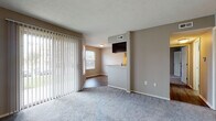 Located at 1551 Causeway Dr. in Dayton, Ohio, this single-floor residence offers a practical and comfortable layout with a clean, neutral aesthetic throughout. The living area is generously sized, finished with plush carpeting and warmed by natural light streaming through large sliding glass doors fitted with vertical blinds that open to an outdoor view. A secondary window in the adjoining dining area further brightens the space. The open-concept design connects the living and dining areas to the kitchen via a pass-through breakfast bar topped with granite countertops — a standout feature of the home. The kitchen is well-equipped with dark espresso cabinetry, stainless steel appliances including a refrigerator and range, and durable hardwood-style flooring. Track lighting overhead adds a modern touch to the culinary space. The bedroom is a quiet retreat, featuring soft carpeting, a window with natural light, and neutral taupe walls. The bathroom is cleanly appointed with a full soaking tub and shower surrounded by classic white tile, a dark-cabinet vanity with a white countertop, a mirrored medicine cabinet, and hardwood-style flooring. Throughout the home, consistent neutral tones and clean finishes create a cohesive and inviting living environment.