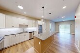 Located at 150 Draper Ave in North Attleborough, MA, this thoughtfully designed 2-bedroom, 2-bathroom residence offers a well-appointed single-floor layout with modern finishes throughout. Light hardwood-style flooring flows seamlessly across every room, complementing the neutral warm-gray palette that creates a clean, cohesive aesthetic.

The open-concept kitchen is a standout feature, showcasing white shaker cabinetry, a subway tile backsplash, granite countertops, and a central island with stylish pendant lighting overhead. Stainless steel appliances — including a refrigerator, dishwasher, range, and microwave — complete the space. The kitchen opens directly into the living area, which benefits from natural light through large sliding glass doors leading to a private patio.

The spacious primary bedroom features dual windows with outdoor views, while the second bedroom also enjoys ample natural light. The unit includes five closets, providing generous storage throughout. Both bathrooms are finished with granite-topped white vanities and hardwood-style flooring — one with a tub/shower combo and the other with a walk-in shower. Additional conveniences include a dedicated laundry area and a utility room. Recessed lighting throughout enhances the bright, modern ambiance of this well-designed home.
