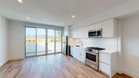 Located at 901 Vine St in the heart of Hollywood, Los Angeles, this contemporary two-story residence showcases a clean, modern design throughout. The open-plan lower level features warm light wood flooring, recessed lighting, and a stylish kitchen equipped with flat-front white cabinetry, stainless steel appliances including a gas range, built-in microwave, dishwasher, and refrigerator, all complemented by sleek white countertops. Large sliding glass doors lead directly to a private balcony, flooding the living area with natural light and framing striking views of the Hollywood Hills and surrounding cityscape. A carpeted staircase connects the lower level to the upper floor, where bedrooms are finished with plush carpet and oversized windows that capture sweeping panoramic views of the Los Angeles skyline and surrounding neighborhoods. The upper level also features mirrored sliding closet doors, maximizing both storage and the sense of space. The bathroom is appointed with marble-style tile surround, a soaking tub, and a clean white vanity, contributing to the home's refined, minimalist aesthetic. Throughout, the design balances modern finishes with an airy, light-filled ambiance ideal for urban living in Los Angeles.