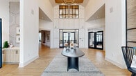 Located at 601 Cambrian Ridge Trail in Wake Forest, NC, this single-story amenity facility delivers an impressive combination of architectural sophistication and functional design across ten thoughtfully appointed spaces. The grand entrance immediately establishes the building's character with soaring double-height ceilings, a striking clerestory window with black steel framing, and herringbone-patterned hardwood flooring. A contemporary black console table anchors the foyer, drawing the eye toward glass-panel doors that frame views of the surrounding community.

The lounge area continues the dramatic vertical scale, featuring shiplap accent walls, floor-to-ceiling windows, and a built-in counter workspace that overlooks the outdoors. A stylish social lounge offers a more intimate atmosphere, with circular tray ceilings, textured wallcovering, leather banquette seating, and warm gold-accented furnishings. A dedicated meeting room showcases a dark stone-topped conference table beneath oversized pendant lights and a navy tile feature wall with open shelving.

Fitness amenities are extensive, with a well-equipped strength and cardio gym featuring high ceilings, large windows, and mirrored walls, complemented by a separate studio outfitted with cycling bikes, rowing machines, and direct outdoor access. Decorative touches like an arched built-in nook and an ornamental perforated metal wall panel add refined character throughout.