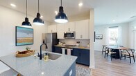 Located at 347 Arboretum Dr in Wilmington, NC, this single-floor residence combines contemporary design with thoughtful functionality throughout its well-planned layout. Light wood-tone flooring flows seamlessly across all rooms, creating a cohesive and inviting atmosphere.

The kitchen serves as a standout centerpiece, showcasing a striking two-tone design with navy lower cabinetry and crisp white upper cabinets. A large island with speckled quartz countertops and a matte black sink anchors the space, illuminated by bold industrial pendant lights. Stainless steel appliances, including a French door refrigerator, range, and microwave, complement a geometric tile backsplash.

The open-concept living area connects naturally to a bright dining nook surrounded by multiple windows that invite natural light. The living room offers generous proportions with a ceiling fan overhead.

Each bedroom features ceiling fans, natural light from well-positioned windows, and ample room for furnishings. The primary bathroom is particularly notable, featuring a granite-topped vanity, a glass-enclosed shower, and direct access to a walk-in closet with built-in shelving. A second full bathroom includes a subway-tiled soaking tub, granite counters, and matte black fixtures. An in-unit laundry area with a full-size washer and dryer adds everyday convenience.