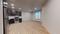 Located at 6416 Bridge Rd in Monona, Wisconsin, this thoughtfully designed single-floor unit offers a clean, modern aesthetic throughout. Light wood-look flooring runs seamlessly across the open living area, creating a bright and cohesive atmosphere complemented by recessed lighting and neutral gray walls.

The kitchen is a standout feature, equipped with a full suite of stainless steel appliances including a range with microwave above, dishwasher, and refrigerator. Rich dark espresso cabinetry with matte black hardware is paired with crisp white quartz countertops and a classic white subway tile backsplash, delivering a striking contrast that anchors the space. Ample upper and lower cabinet storage ensures excellent functionality.

The open living area is generously proportioned, offering flexible layout options, and includes a ceiling fan for added comfort. Natural light enters through a window fitted with a baseboard heating unit beneath it. A dedicated entry area leads to a convenient in-unit stacked washer and dryer, adding everyday practicality.

The bathroom features a walk-in shower with clean white surrounds and a matte black grab bar, reflecting the consistent modern design language found throughout the unit. Overall, this space presents a well-appointed, move-in-ready environment with contemporary finishes and efficient use of space.
