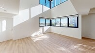 Located in the Van Nuys neighborhood of Los Angeles, this contemporary two-story residence showcases a clean, modern design defined by crisp white walls and light-toned hardwood flooring throughout. The upper level is a standout architectural achievement, featuring dramatically tall ceilings and an expansive wraparound window system framed in sleek black trim. These floor-to-ceiling and clerestory windows flood the space with abundant natural light and offer sweeping panoramic views of the surrounding Los Angeles cityscape, including palm trees and neighboring skyline elements. A staircase with a modern metal railing connects the two levels, which are revealed in the 3D model to offer a well-organized, open layout. The kitchen is outfitted with white shaker cabinetry extending to the ceiling, light quartz countertops, a double-basin stainless steel sink, and stainless steel appliances including a refrigerator and dishwasher. Bedrooms are bright and airy, with large windows and mirrored sliding-door closets. Both bathrooms feature a clean, all-white aesthetic with tiled tub-shower combos, modern vanities, and round mirrors. A dedicated laundry area houses a full-size Samsung front-loading washer and dryer. The overall ambiance is bright, minimalist, and move-in ready.
