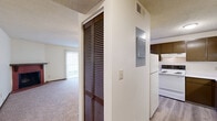 Located at 3650 N Academy Blvd in Colorado Springs, CO, this one-bedroom, one-bathroom unit offers a practical and well-organized single-floor layout. The combined kitchen and living room area serves as the heart of the space, featuring a standout corner brick fireplace that adds warmth and character to the living area. Plush carpeting extends throughout the living spaces, while the kitchen transitions to smooth hard-surface flooring. The kitchen is equipped with dark espresso-toned cabinetry, white appliances including a range, dishwasher, and refrigerator, along with ample counter space and an under-cabinet range hood. A sliding glass door in the living area opens to a balcony, allowing natural light to fill the room. The spacious bedroom features large vertical-blind windows, soft carpet, and a closet, offering a quiet and comfortable retreat. A hallway connects the bedroom to the full bathroom, which includes a tub-shower combination with white tile surround, a vanity with marble-style countertop, and wood-toned cabinetry with hard-surface flooring. An in-unit utility panel and laundry hookup add everyday convenience to this efficiently designed Colorado Springs home.