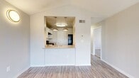 This single-story, 2-bedroom, 2-bathroom home offers a thoughtfully designed layout that maximizes functionality and comfort. The living area features vaulted ceilings and wood-style plank flooring, creating an open and airy atmosphere. Natural light filters in through large windows dressed with horizontal blinds, enhancing the bright, neutral color palette throughout.

The kitchen is open to the living space via a peninsula counter with a sink and light-toned countertops, white cabinetry with subway tile backsplash, and black appliances including a range, dishwasher, and refrigerator. Two pendant lights with gold-tone fixtures illuminate the kitchen area, adding a stylish touch.

A central hallway connects the main living areas to the bedrooms and bathrooms, with an electrical panel conveniently located nearby. Both bedrooms are carpeted and include closets with wire shelving systems; one bedroom features mirrored sliding closet doors and a window with outdoor views. Each bathroom includes a full tub-shower combination with white tile surround, one featuring a window for added natural light and wood-style flooring.

The in-unit laundry area accommodates a full-size washer and dryer with overhead wire shelving, offering practical convenience. The home's clean, neutral finishes provide a versatile and move-in-ready living environment.
