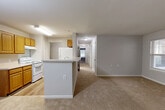 This single-floor, 3-bedroom, 2-bathroom residence on Keelingwood Circle offers a functional and comfortable layout designed for everyday living. The open-concept kitchen, dining, and living area serves as the heart of the home. The kitchen features warm honey-toned wood cabinetry, light countertops, hardwood-style flooring, and white appliances including a range and refrigerator, with a peninsula that connects seamlessly to the carpeted living and dining space. The living area is generously sized, bathed in natural light from multiple windows, and includes direct access to a private balcony — ideal for enjoying outdoor views. A central hallway leads to all three bedrooms, each finished with soft carpet and neutral gray walls. The spacious primary bedroom includes mirrored sliding closet doors and an en-suite bathroom. A total of six closets throughout the home provides exceptional storage capacity. Both bathrooms feature wood-tone vanities, light countertops, and hardwood-style flooring. A dedicated in-unit laundry area with washer and dryer hookups adds everyday convenience. The consistent use of neutral tones and soft carpeting throughout creates a calm, cohesive ambiance across the entire home.