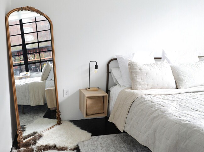 Ventanas de fábrica, dormitorio, vista de la línea de cintura y espejo vintage dorado - Ford Factory Lofts