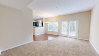 This two-story home offers a thoughtfully designed layout with four bedrooms, five bathrooms, and dedicated spaces for everyday living. The main floor features an open-concept living and dining area distinguished by rich hardwood flooring, neutral warm-toned walls, and a textured ceiling. A chandelier anchors the dining space, while large windows and glass French doors flood the area with natural light and provide views of the surrounding greenery. The kitchen is equipped with dark cabinetry, stone-look countertops, a double sink beneath a window, and a pass-through breakfast bar that connects seamlessly to the dining area. The upper floor houses the bedrooms, all carpeted in a warm neutral tone. The primary bedroom is a well-proportioned retreat accompanied by a spacious walk-in closet outfitted with wire shelving and hanging rods. Additional bedrooms feature windows with neighborhood views, providing a bright and airy atmosphere. The home includes three closets in total, offering generous storage. A dedicated laundry room with built-in shelving and dryer venting adds everyday convenience. The five bathrooms include tile-floored designs with tub-shower combinations. A white-railed staircase connects both floors through a carpeted hallway, completing the home's clean, practical aesthetic.