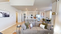 This well-appointed two-story home in Loveland, Colorado offers a thoughtfully designed layout spread across two floors. The main level opens into a bright, open-concept living, dining, and kitchen area finished with light hardwood-style flooring throughout. The kitchen is a standout feature, boasting gray shaker-style cabinetry, stainless steel appliances including a gas range and French door refrigerator, a subway tile backsplash, and a large center island with bar seating — ideal for both casual dining and entertaining. A dedicated pantry provides ample storage. The adjacent dining area benefits from natural light streaming through a large window, while the living room offers vaulted ceiling height, a ceiling fan, and an abundance of windows that keep the space bright and airy. Upstairs, the more expansive floor houses all three bedrooms, including a generously sized primary bedroom with plush carpeting, direct access to its own bathroom featuring a dual-sink vanity, wood-look tile flooring, and a glass-enclosed walk-in shower with large-format tile surround. The additional bedrooms are well-proportioned and share access to additional bathrooms. A dedicated upstairs laundry room with full-size washer and dryer adds everyday convenience. Two closets and hallways complete the upper floor's functional layout.