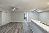 Located at 2277 Arbour Walk Cir in Naples, FL, this single-floor, 2-bedroom, 2-bathroom residence offers a thoughtfully designed layout with clean, modern finishes throughout. Wood-look plank flooring flows consistently across the living areas, lending a cohesive and contemporary feel to the space.

The open-concept kitchen is a standout feature, showcasing white shaker-style cabinetry, a quartz-topped peninsula with an integrated sink, stainless steel appliances including an electric range, and a black refrigerator. Track lighting illuminates the kitchen, while the peninsula provides a natural transition into the combined dining and living area. A ceiling fan and sliding glass door with views of lush greenery make the living space feel bright and airy.

Both bedrooms are comfortably sized, each equipped with a ceiling fan and louvered bi-fold closet doors. Natural light filters through windows framing tree-lined outdoor views. The primary bedroom offers generous closet space.

The two bathrooms are finished in a clean, all-white palette, each featuring a vanity with quartz countertops, a tub-shower combo with tile surround, and wood-look flooring. One bathroom includes accessibility grab bars. A dedicated laundry area with a top-loading washer adds everyday convenience. Three closets and a hallway complete this efficiently arranged and well-maintained residence.