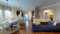 This single-floor residence offers a thoughtfully designed open-concept layout where the living, dining, and kitchen areas flow seamlessly together. Rich hardwood-style flooring runs throughout the main living spaces, complemented by elegant crown molding that adds a refined architectural touch. The living room is a comfortable and welcoming space, anchored by a tufted sofa and a classic wooden entertainment armoire. A dining nook with a bay window configuration floods the area with natural light, creating a bright and airy atmosphere ideal for everyday meals.

The kitchen is well-equipped with dark cabinetry, granite countertops, stainless steel appliances, and ample storage. A breakfast bar provides additional seating, enhancing the kitchen's functionality.

The primary bedroom is generously proportioned, featuring plush carpet flooring, a ceiling fan, and dark curtains that lend a cozy, restful ambiance. The second bedroom also offers carpeted flooring and convenient access to a walk-in closet, providing excellent storage. The full bathroom includes a tub-shower combination, wood-toned cabinetry, and hardwood-style flooring. Completing the layout is a dedicated in-unit laundry room with full-size washer and dryer and built-in shelving.