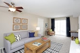 This single-floor residence offers a well-organized layout with multiple bedrooms, a living area, kitchen, and bathroom. The living room is an inviting space featuring wood-look flooring, a textured ceiling, and a ceiling fan. A large sliding glass door fills the room with natural light and provides access to an outdoor area, while neutral-toned walls create a warm, versatile backdrop throughout.

The kitchen is finished with dark cabinetry, granite-look countertops, black appliances, and a mosaic tile backsplash, combining a sleek, modern aesthetic with practical functionality. Each bedroom features plush carpeting, large windows with curtain panels that allow for natural light, and ample closet space. The bedrooms are generously proportioned, accommodating full-sized furniture with ease.

The bathroom includes a full tub-shower combination with white tile surround, wood-look flooring, and granite-look countertop surfaces, maintaining a clean and consistent finish. Throughout the unit, the neutral color palette, textured ceilings, and consistent flooring materials contribute to a cohesive and comfortable living environment suitable for everyday use.