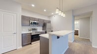 This thoughtfully designed one-bedroom, one-bathroom residence in Etna, Ohio offers a well-appointed single-floor layout with modern finishes throughout. The open-concept kitchen and living area serves as the heart of the home, anchored by a central island with striking marble-look countertops and an undermount sink. Pendant lighting illuminates the island, while rich dark-toned cabinetry provides ample storage. The kitchen is fully equipped with a complete suite of stainless steel appliances, including a range, over-the-range microwave, and refrigerator. Light wood-style flooring runs throughout the kitchen and living areas, creating a seamless, contemporary feel. The living room features a ceiling fan and French doors that open onto a private balcony, filling the space with natural light. The bedroom is carpeted for comfort, offering natural light through a window and access to two closets. The bathroom includes a tub-shower combination, a single-sink vanity with marble-look countertop, and matching dark cabinetry. Additional conveniences include a dedicated laundry area, a pantry, a utility room, and hallway storage, making this a highly functional and stylish residence.