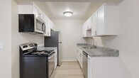 This single-floor residence offers a clean, neutral aesthetic defined by light-toned finishes and a practical layout. The open living area is finished with light wood-style flooring and features a large sliding glass door dressed with vertical blinds, allowing abundant natural light to fill the space while providing access to an outdoor area with green views.

The galley-style kitchen is well-equipped, featuring white shaker cabinetry, gray marbled countertops, and a full suite of stainless steel appliances including a range, over-the-range microwave, refrigerator, and dishwasher. Light wood flooring continues through this space, complementing the bright, crisp cabinetry.

The bedrooms are carpeted for comfort and are generously sized. One bedroom includes direct access to a walk-in closet, offering notable storage capacity. Sliding glass doors in the bedroom also connect to an outdoor area, bringing in additional natural light and outdoor views.

The bathroom is finished with full white square tile surrounding a soaking bathtub, maintaining the clean and neutral character carried throughout the unit. Overall, the space presents a cohesive, understated design with functional details throughout.