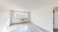 Located at 128 North Street in Newton, MA, this two-bedroom, one-bathroom unit offers a practical and well-organized single-floor layout. Consistent hardwood-style flooring flows throughout the space, lending a clean, cohesive look to every room.

The kitchen is equipped with ample white cabinetry, a full suite of white appliances including a refrigerator, electric range, and dishwasher, and a single-basin sink. Light countertops and a neutral color palette keep the space feeling open and functional.

Both bedrooms feature the same hardwood-style flooring and are served by baseboard heating units along the walls. The primary bedroom is a comfortable size and benefits from two windows that invite natural light and views of surrounding greenery. The second bedroom is a well-proportioned space with additional baseboard heating and access to natural light.

The bathroom includes a full tub-shower combination with tiled surround, a toilet, and a vanity with storage, all finished in a clean white palette.

A hallway connects the main areas of the unit and includes an entry door with a deadbolt. Throughout, the neutral wall tones and light flooring create a bright, airy ambiance suited to a variety of furnishing styles.