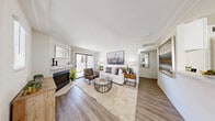 Located at 1800 N Green Valley Parkway in Henderson, Nevada, this one-bedroom, one-bathroom residence offers a thoughtfully designed single-level floor plan that makes efficient use of its space. Light-toned walls, crown molding, and wood-style flooring run throughout, creating a cohesive and contemporary aesthetic.

The living room serves as the heart of the home, featuring a fireplace, crown molding, and a sliding glass door that opens to a private patio, filling the space with natural light and outdoor views. Adjacent to the living room, the dedicated dining area benefits from multiple windows, a ceiling fan, and ample room for a full dining set.

The kitchen is well-appointed with white shaker cabinetry, quartz countertops, a breakfast bar peninsula, and a full suite of stainless steel appliances including a gas range, microwave, dishwasher, and refrigerator. A hallway off the kitchen leads to the in-unit laundry area, adding everyday convenience.

The bedroom is a comfortable and serene retreat with a large window, generous closet space, and the same warm wood-style flooring found throughout the home. The bathroom is clean and functional, featuring a full tub-shower combination with white tile surround and a vanity with quartz countertop.