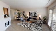 This single-floor residence offers a thoughtfully organized layout with distinct living, dining, sleeping, and kitchen areas connected by a cohesive contemporary design. The living room serves as the central gathering space, featuring light wood-style flooring, a ceiling fan, and large French doors that invite abundant natural light. The open arrangement accommodates both a dedicated seating area and an adjacent dining space, creating a versatile and comfortable atmosphere.

The kitchen is efficiently designed with warm honey-toned cabinetry, granite-style countertops, a mosaic tile backsplash, and a full suite of stainless steel appliances including a gas range, microwave, and refrigerator. A window above the sink provides additional natural light to the workspace. A pass-through opening connects the kitchen to the living and dining area, enhancing the open feel.

The primary bedroom is generously proportioned, featuring plush carpeting, natural light from a large window, and access to a walk-in closet. A second bedroom offers similar comfort with carpeted flooring, a wide window, and a standard closet. The bathroom presents a clean, neutral palette with a full soaking tub and shower combination, a single vanity, and understated finishes throughout.