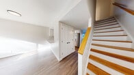 Located at 66 Village Way in Brookline, MA, this three-bedroom, two-bathroom home spans three well-proportioned floors, offering a functional and modern living experience. Hardwood-style flooring flows consistently throughout, lending warmth and cohesion to every level.

The main floor features two living areas and a thoughtfully designed kitchen equipped with white shaker cabinetry, a marble-style tile backsplash, quartz countertops with a breakfast bar peninsula, and stainless steel appliances including a range and over-the-range microwave. A dedicated laundry area with an in-unit washer is also conveniently included.

The three bedrooms are bright and well-sized, with the spacious primary bedroom offering generous room to furnish comfortably. Bedrooms feature large windows and sliding glass doors that invite natural light and offer views of the surrounding brick exterior. Closets with built-in shelving provide ample storage.

Both bathrooms are finished with clean, white fixtures and matte black hardware. One bathroom features stone-look tile flooring and a full tub-shower combination with a white vanity. A staircase with warm wood-toned railings and white balusters connects the three floors. The overall aesthetic is clean, modern, and move-in ready.