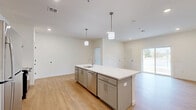 Located at 15 Ore Bank Rd in Dillsburg, PA, this single-floor, 2-bedroom, 2-bathroom unit offers a clean, modern design with consistent finishes throughout. Light-toned luxury vinyl plank flooring runs through the main living areas, kitchen, and bathrooms, while plush carpet covers both bedrooms, adding warmth and comfort.

The open-concept kitchen is a standout feature, equipped with gray shaker-style cabinetry, white quartz countertops, stainless steel appliances including a refrigerator, range, and dishwasher, and a large island with pendant lighting and a built-in sink. The kitchen flows naturally into the living area, which features recessed lighting and a sliding glass door that brings in natural light and provides outdoor views.

Both bedrooms are carpeted and include windows with blinds. The primary bedroom offers a comfortable footprint, while the secondary bedroom is more compact. The two bathrooms differ in function: one is a full bath with a tub/shower combo and gray vanity, and the other is an accessible bathroom with grab bars, LVP flooring, and an open floor drain. A dedicated laundry room accommodates a front-loading washer or dryer with overhead wire shelving, completing this well-appointed and functional unit.
