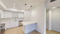 Located in Royal Palm Beach, FL, this thoughtfully designed single-floor residence offers a clean, modern aesthetic with light wood-style flooring and crisp white walls throughout. The open-plan kitchen and living area serves as the heart of the home, featuring sleek white flat-front cabinetry, a subway tile backsplash, stainless steel appliances including a range, microwave, and dishwasher, and a peninsula with a white countertop illuminated by stylish pendant lighting — ideal for casual dining or entertaining. The living area is bright and airy, with recessed lighting and direct access to a private patio that brings in natural greenery views. The bedroom is a serene retreat, benefiting from a large window with outdoor views, a ceiling fan, and warm natural light filtered through horizontal blinds. Three closets — including a well-organized walk-in with wire shelving — provide generous storage. The bathroom is finished to a high standard, showcasing a glass-enclosed walk-in shower with white subway tile, decorative accent strips, and a mosaic tile floor. An in-unit laundry area and a hallway complete this efficiently laid-out, move-in-ready home.