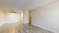 This 2-bedroom, 1-bathroom single-floor unit is designed with a clean, neutral aesthetic and consistent light wood-style vinyl flooring throughout. The living room serves as the central gathering space, featuring a textured ceiling, a ceiling fan with integrated lighting, and a front-facing window fitted with horizontal blinds that allow natural light to filter in alongside a front entry door. A sliding glass door with vertical blinds in the space provides additional outdoor access and natural light.

The galley-style kitchen is efficiently laid out with white shaker cabinetry, quartz-style countertops, a subway tile backsplash, a single-basin undermount sink with a brushed gold faucet, and stainless steel appliances including a range and dishwasher.

The two bedrooms maintain the same light flooring and neutral wall tones, each featuring windows with blinds. The primary bedroom includes a ceiling fan, while the secondary bedroom offers a well-proportioned layout with natural light. A hallway connects the bedrooms to the shared bathroom, which features a white vanity with a quartz-style countertop, an undermount sink, and a glass-enclosed shower.