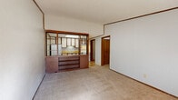 Located on Collins Road in Jacksonville, Florida, this single-story 2-bedroom, 1-bathroom home offers a practical and efficiently organized layout. The combined living and dining room serves as the heart of the home, featuring neutral carpet flooring, wood crown molding, and a textured ceiling. A standout architectural detail is the wood-framed, open-shelf room divider with a built-in cabinet base that visually separates the living area from the kitchen, adding a retro character to the space. The kitchen is bright, with overhead cabinetry, a skylight-style ceiling fixture, and tile flooring. Both bedrooms are carpeted and include ceiling fans with light fixtures, windows that allow in natural light, and closet access — one bedroom also features a built-in under-window cabinet with floor vents. The single bathroom is clean and functional, appointed with wood-look tile flooring, a white vanity with a solid countertop, and a full tub-shower combination. Additional spaces include an entrance, a utility room, and two closets. The property is set among mature trees, providing a naturally shaded exterior setting.